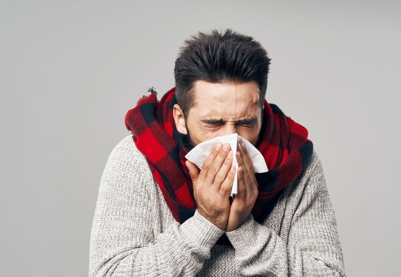 Man with flu sneezing into hankerchief