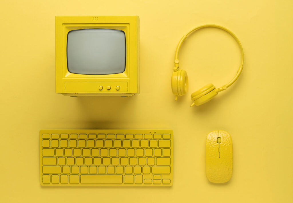 yellow background with yellow computer, headphones, keyboard, and mouse